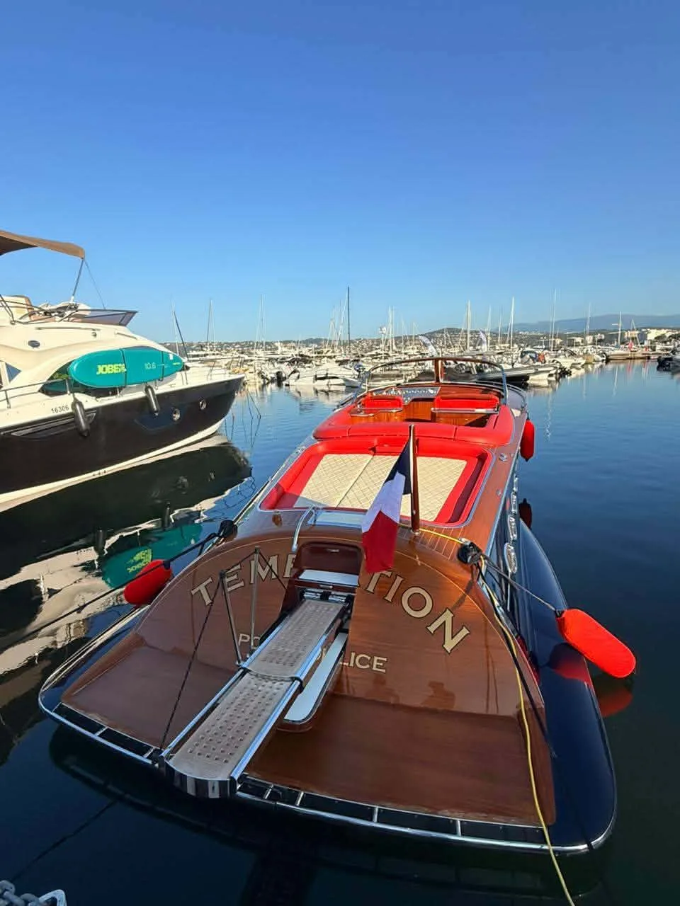 Riva en bois verni et coque rouge amarré au port